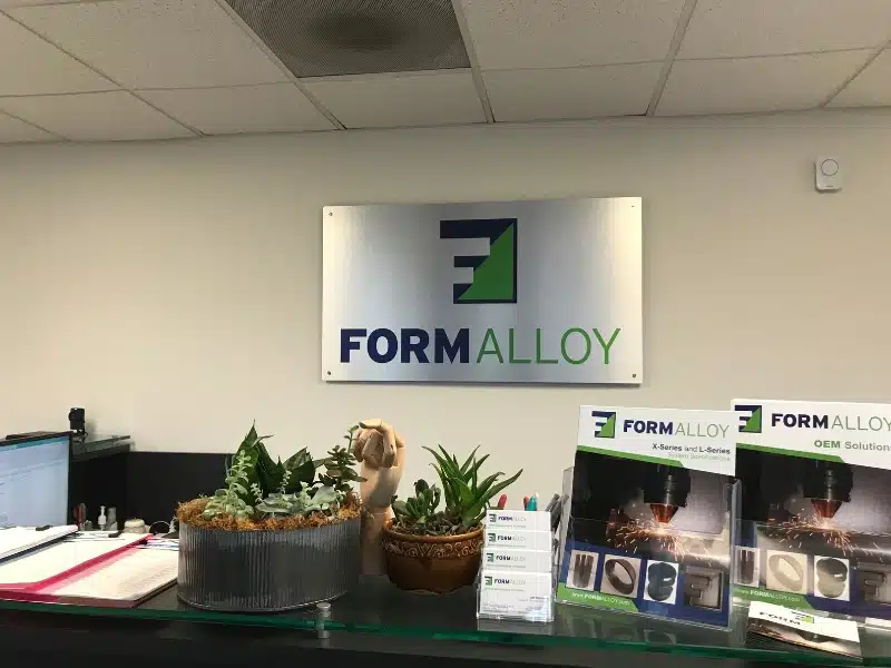 FormAlloy office front desk with company signage, marketing brochures, and branded literature for DED additive manufacturing solutions.