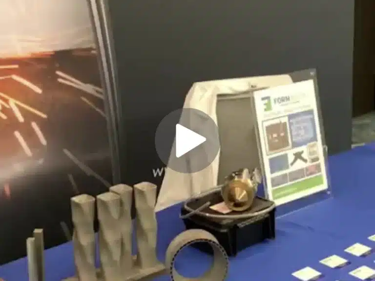 FormAlloy trade show booth featuring metal 3D printed components, DED nozzle display, and promotional materials highlighting Directed Energy Deposition technology.