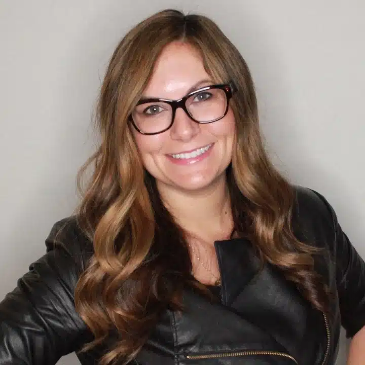 Melanie Lang, Co-Founder and CEO of FormAlloy, smiling in a professional headshot wearing glasses and a black leather jacket.