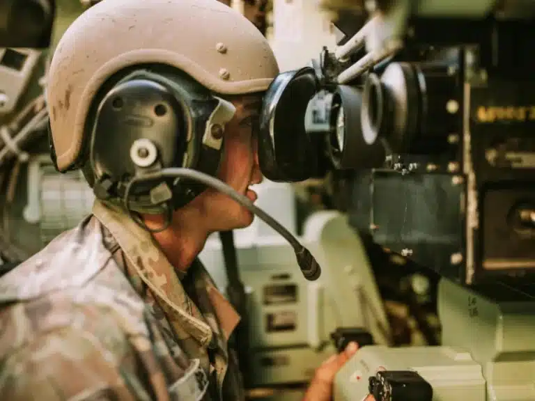 Soldier wearing helmet and headset operating advanced military equipment, highlighting integration of cutting-edge 3D printing technology in defense operations.