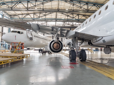 A large airplane parked inside a spacious hangar, showcasing its wings and fuselage.